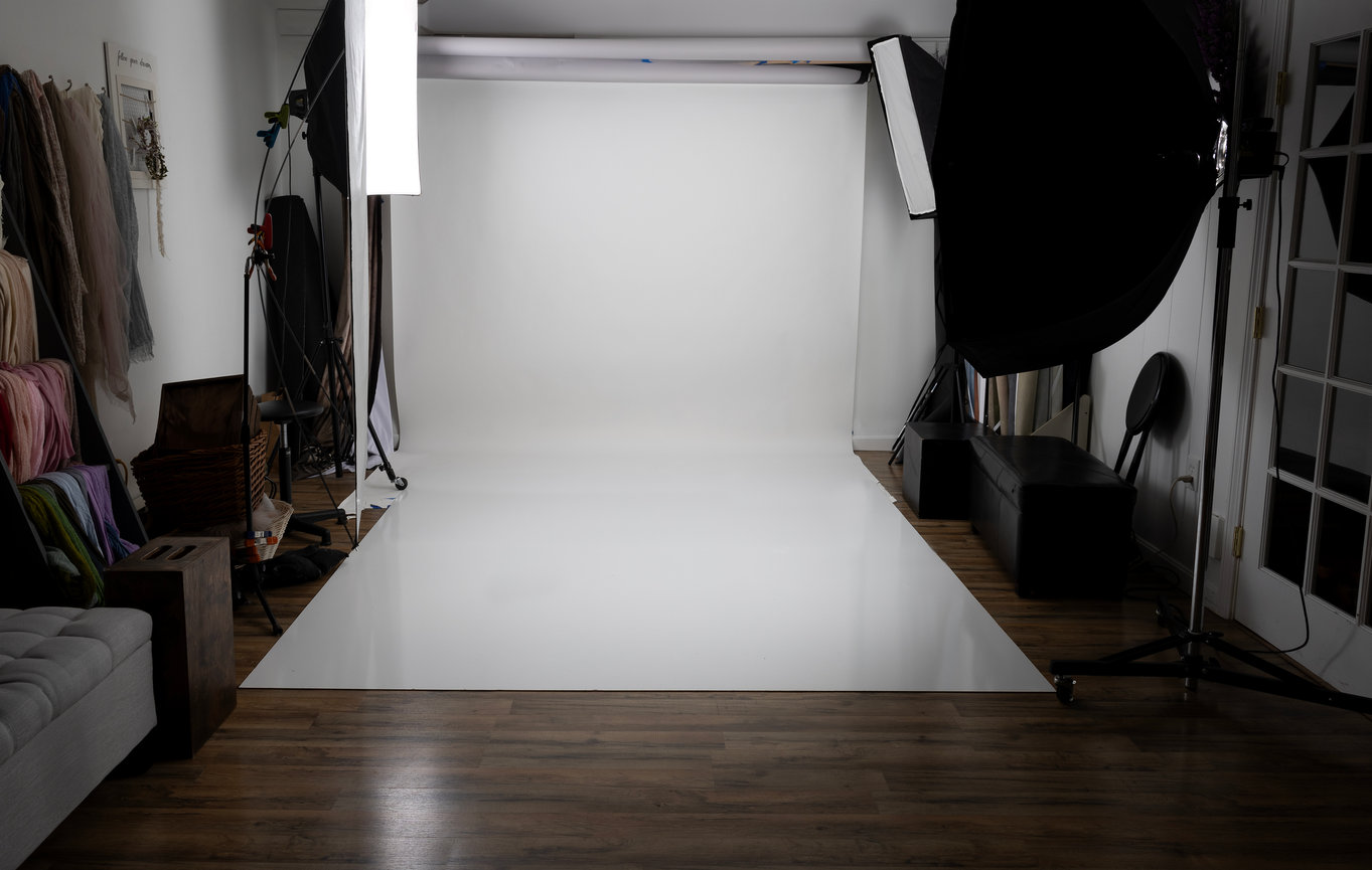 Professional photo studio in Metrowest Boston with white backdrop, soft lighting, and various props around the perimeter.