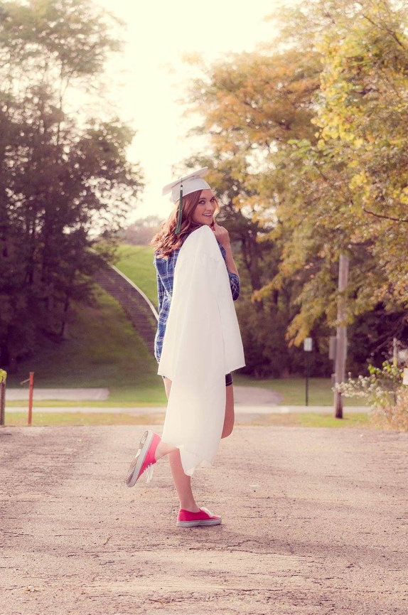 senior girl with cap and gown looking over her shoulder and red shoes