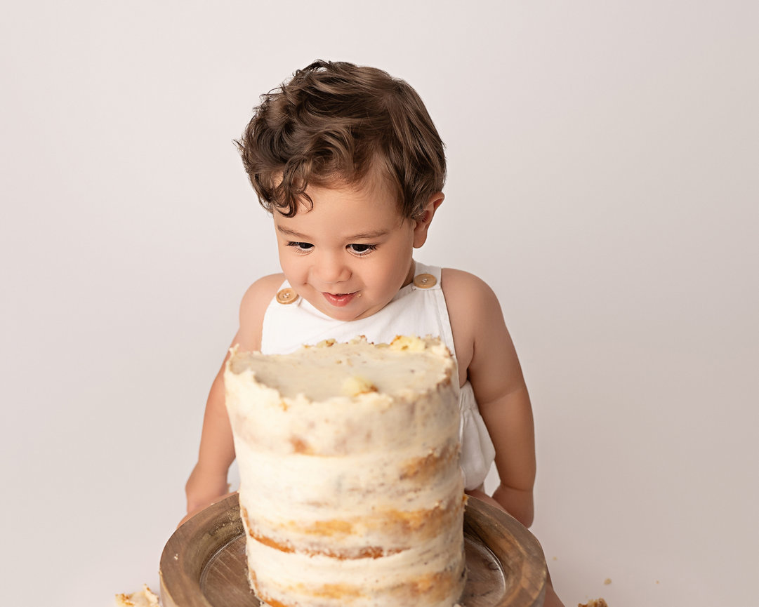 Sweet moment of baby looking at cake with curiosity
