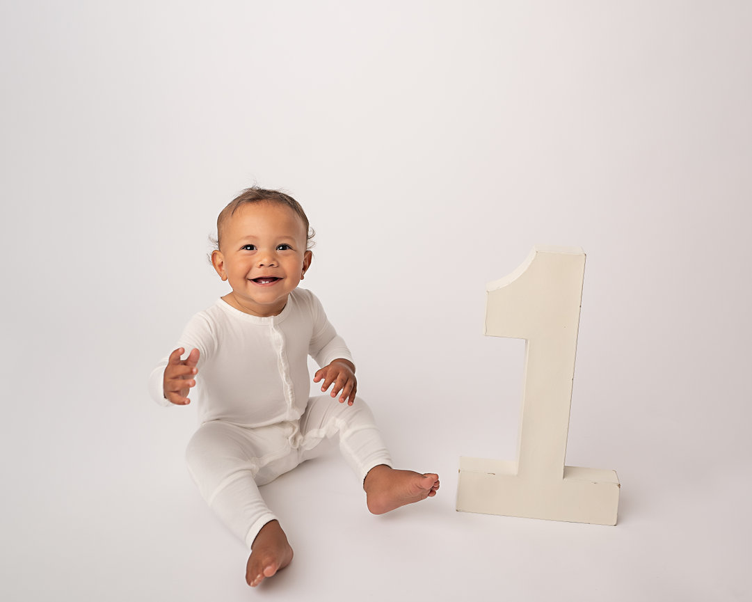 Minimalist birthday portrait with baby smiling in Manasquan next to giant number 1