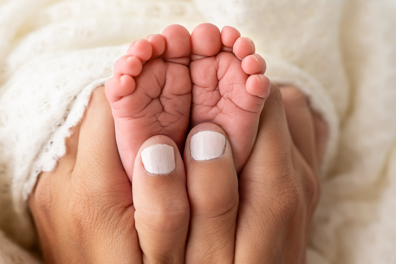 Tiny baby hand resting against mom's fingers in natural light Princeton studio