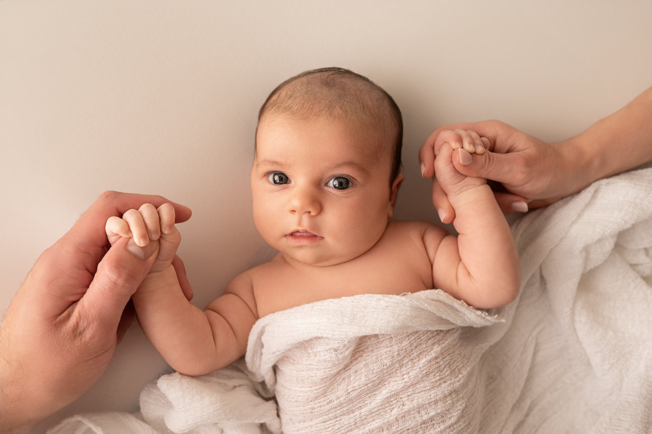 Intimate moment of baby gripping parent fingers in Cranford lifestyle studio