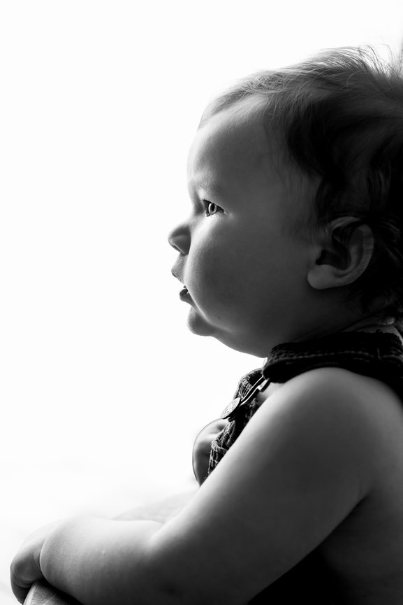 Black and white side profile of a baby looking ahead, with light coming from the background.