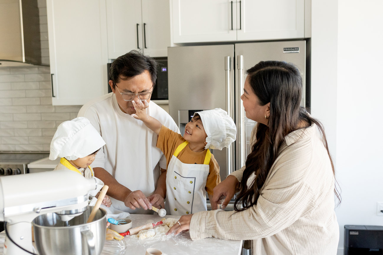 Family baking together in the kitchen, smiling and playfully interacting with flour.