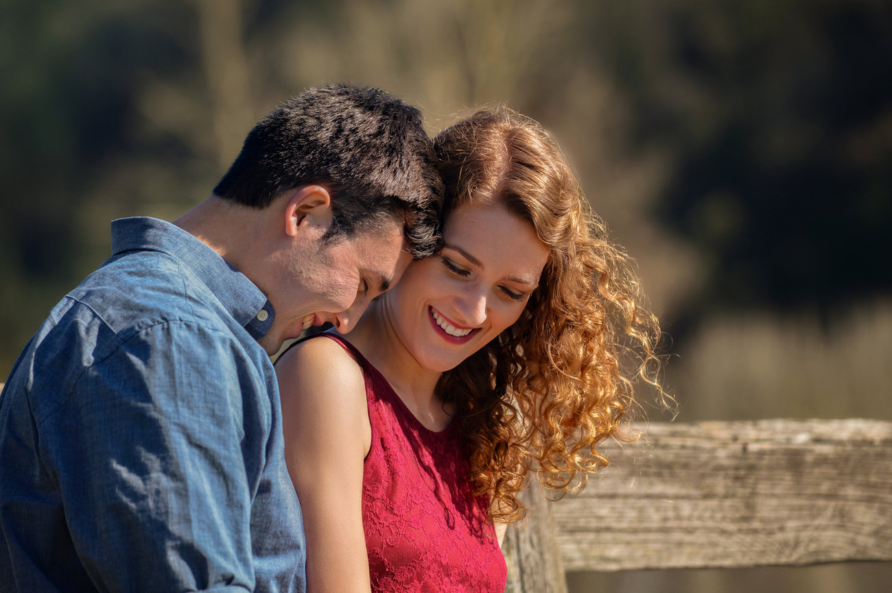 Couple leaning close together outdoors in soft light.
