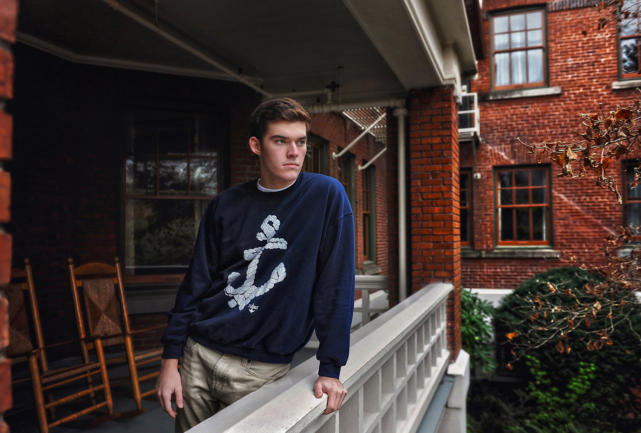 Man standing on a porch outside a brick building.