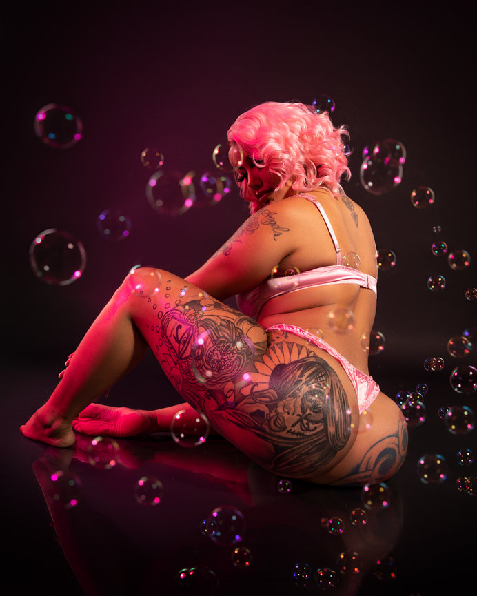 Tattooed woman with bubbles on dark background