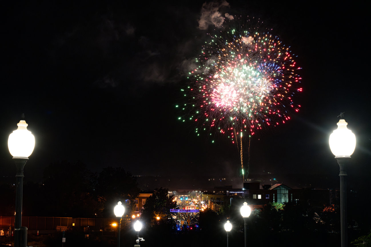 Colorful fireworks bursting over a town skyline at night.