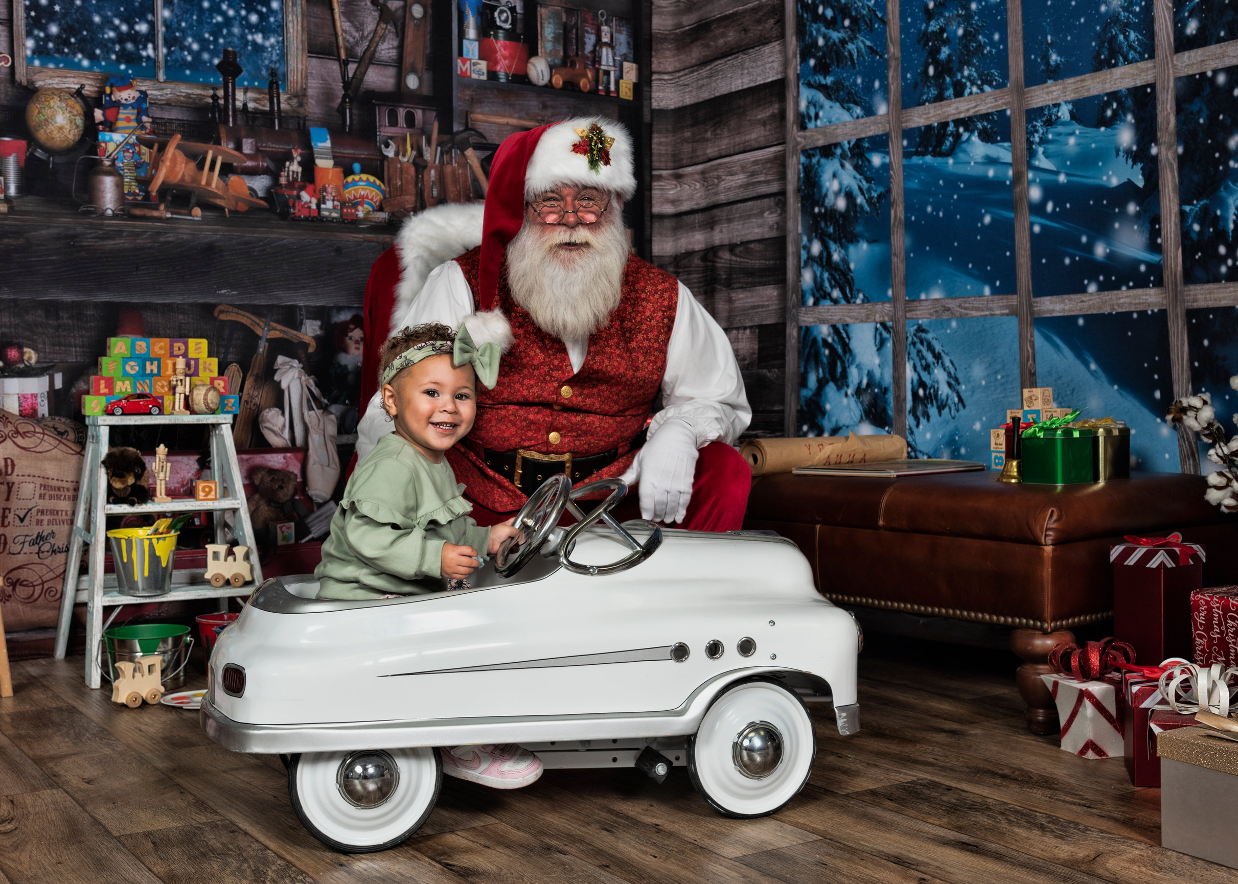 baby sitting in a pedal car in front of santa