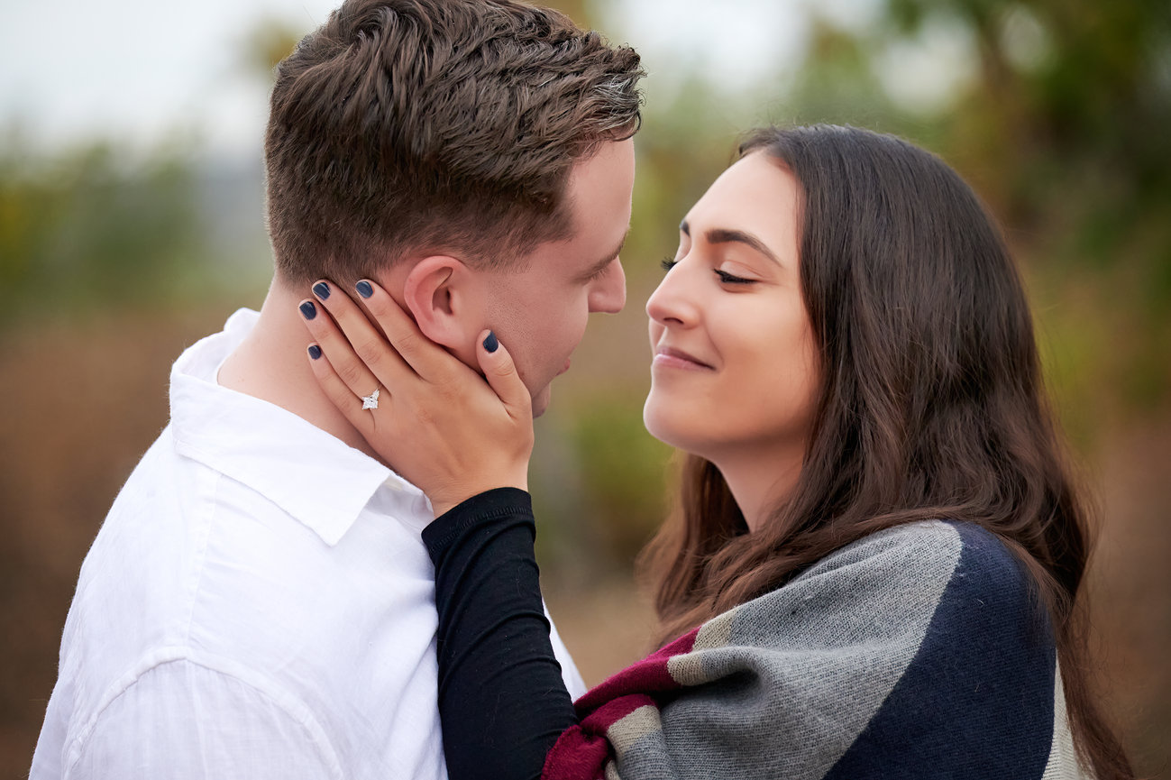 Couple smiling and kissing during outdoor engagement session