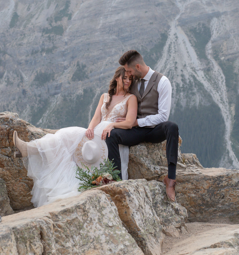 Couple sitting close together on a rocky mountain