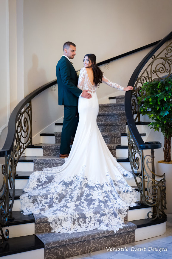 Bride on a curved staircase with her gown train cascading down the steps