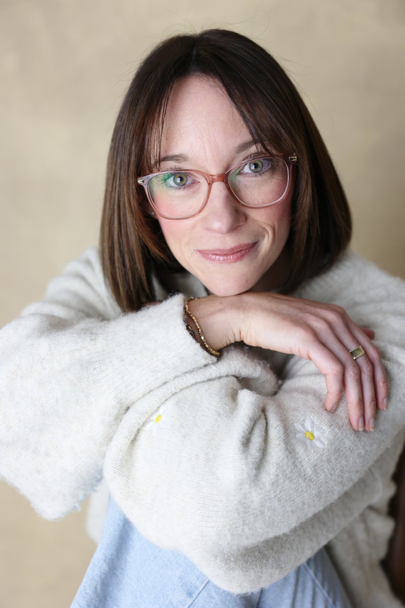 Portrait of a woman with glasses in a cozy white sweater, resting her arms and smiling softly. personal branding photos Melbourne