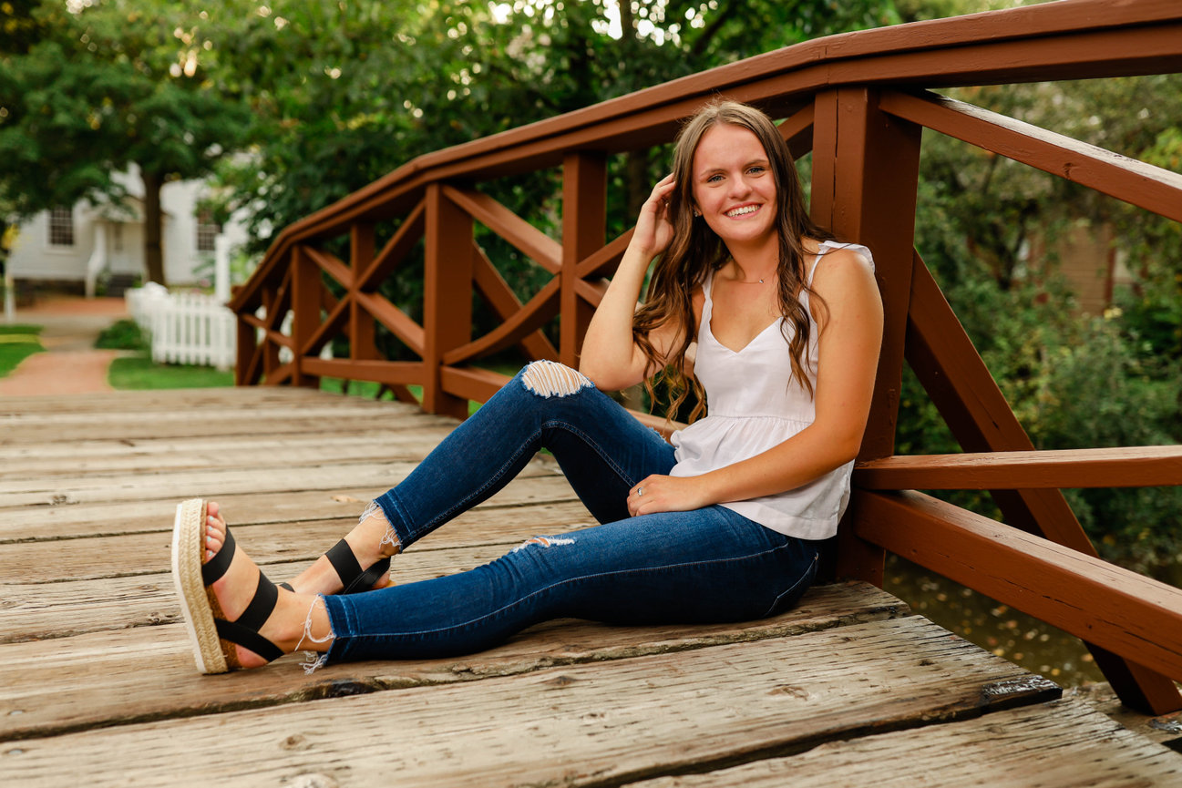 Senior girl seated on bridge during outdoor portrait