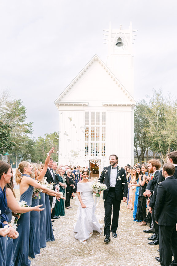 Bride and groom exit their wedding ceremony at Seaside Chapel with flower petals being thrown. Destination wedding photography by Heather Durham.
