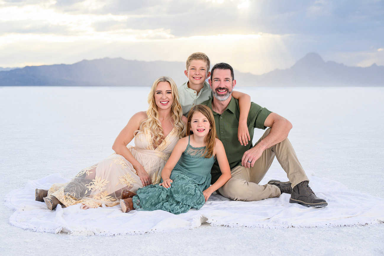 A family photo sitting on the salt flats getting a portrait taken.