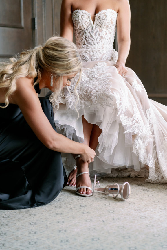 Bride in blush dress and sister helping her put on her shoes. Nashville luxury wedding photography by Heather Durham.