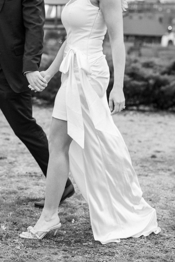 Engaged couple holding hands walking by Cumberland River in Nashville, Tennessee. Engagement photography by Heather Durham.