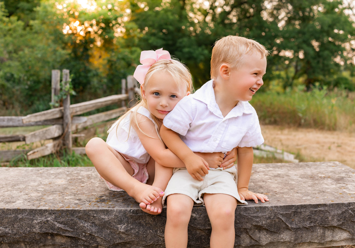 Siblings hugging and laughing together during outdoor family session