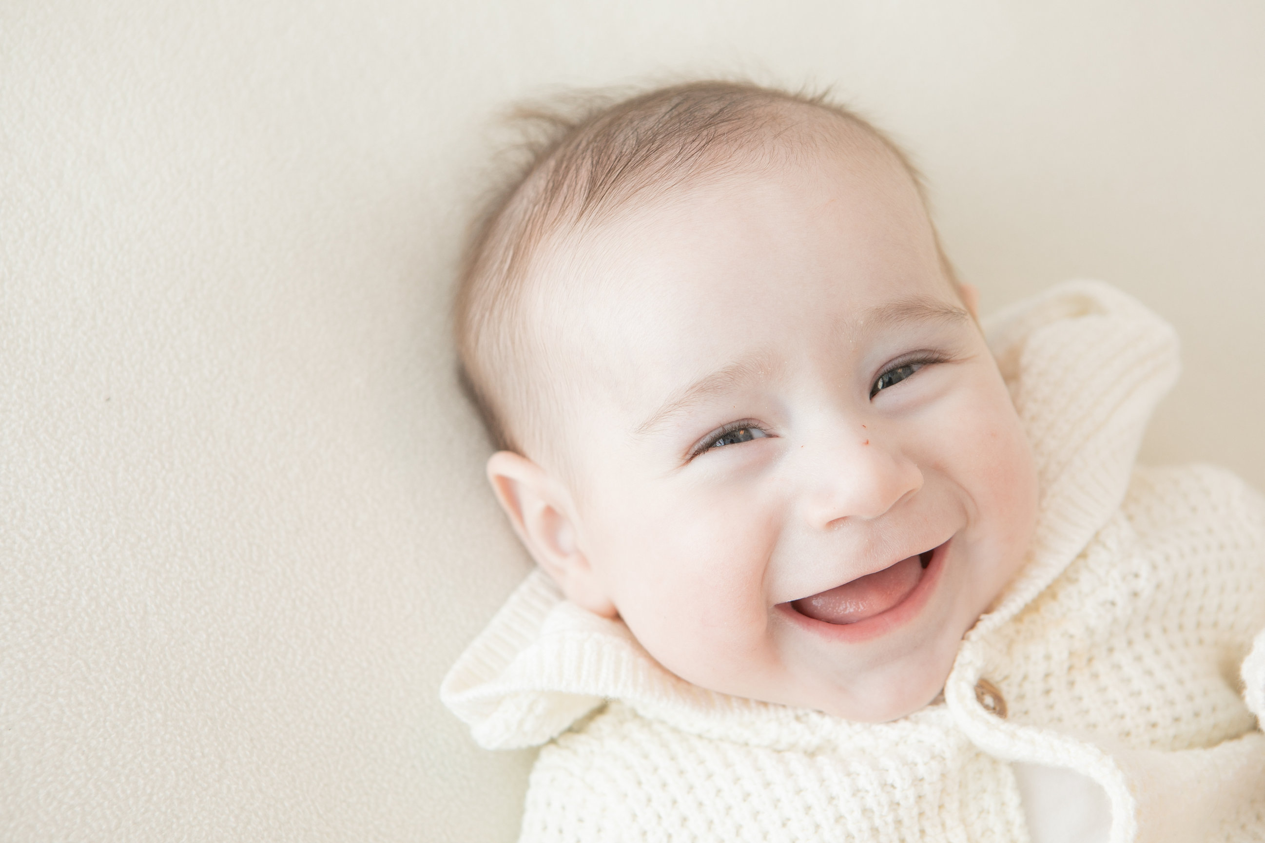 Smiling baby looking towards the camera in a cream outfit