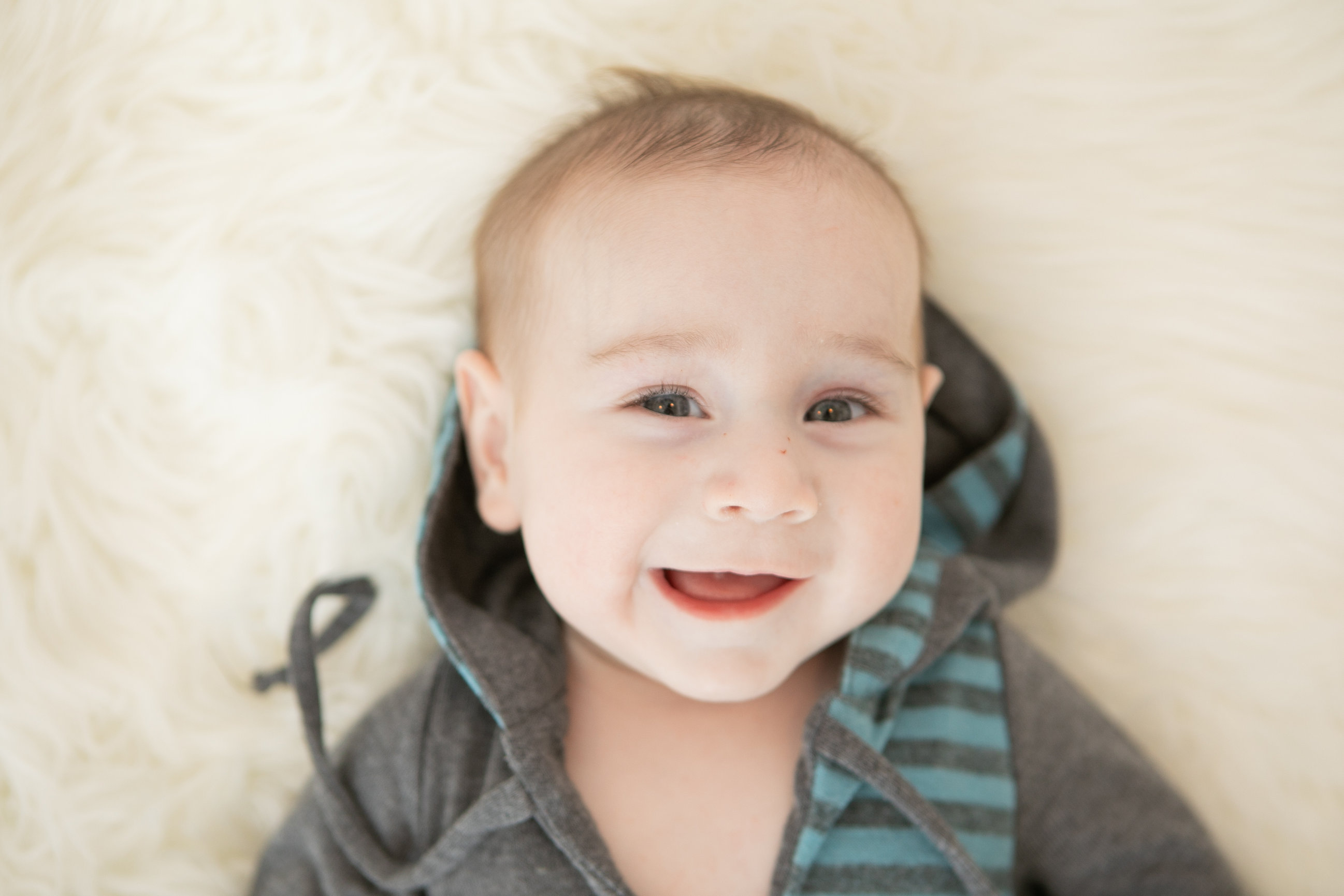 Baby laughing with hands beside their head