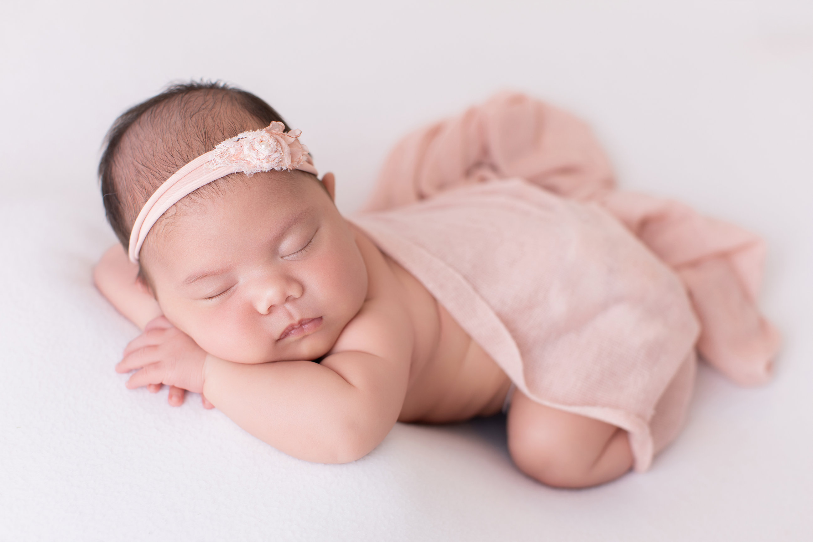 Sleeping newborn girl in a blush wrap, Calgary newborn studio