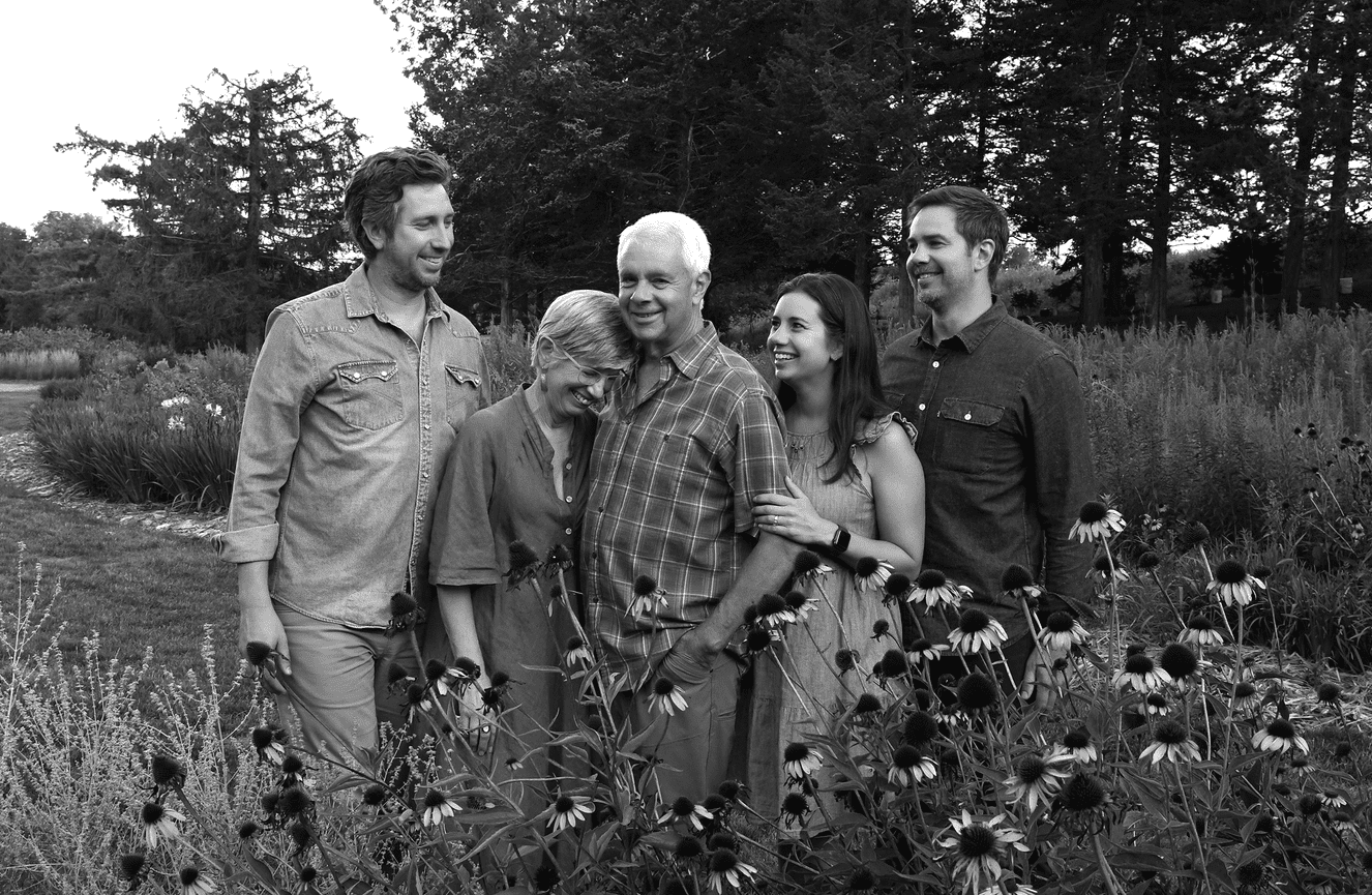 A black and white family photo of five people laughing while standing in a field of flowers in Cedar Rapids, Iowa.