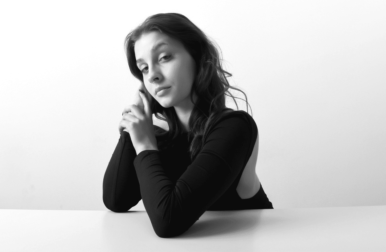 A black and white of a young woman posing in an artful manner.