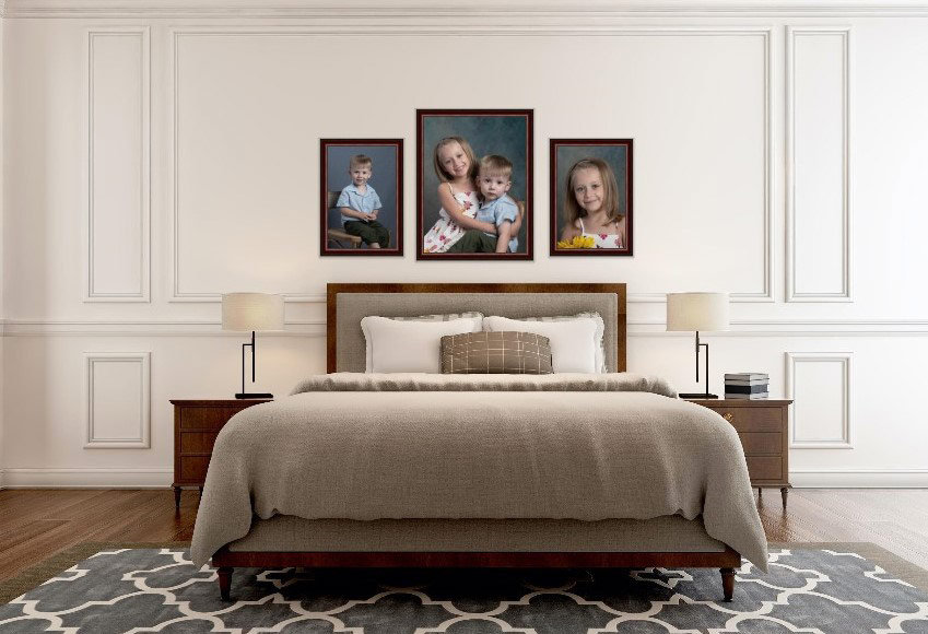Bedroom with a neatly made bed, wooden nightstands, and children framed portraits on a white paneled wall.