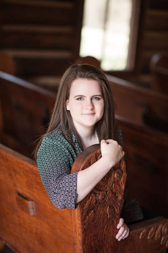 senior girl sitting on pew in Hope Wilderness Chapel at Dogwood Canyon 