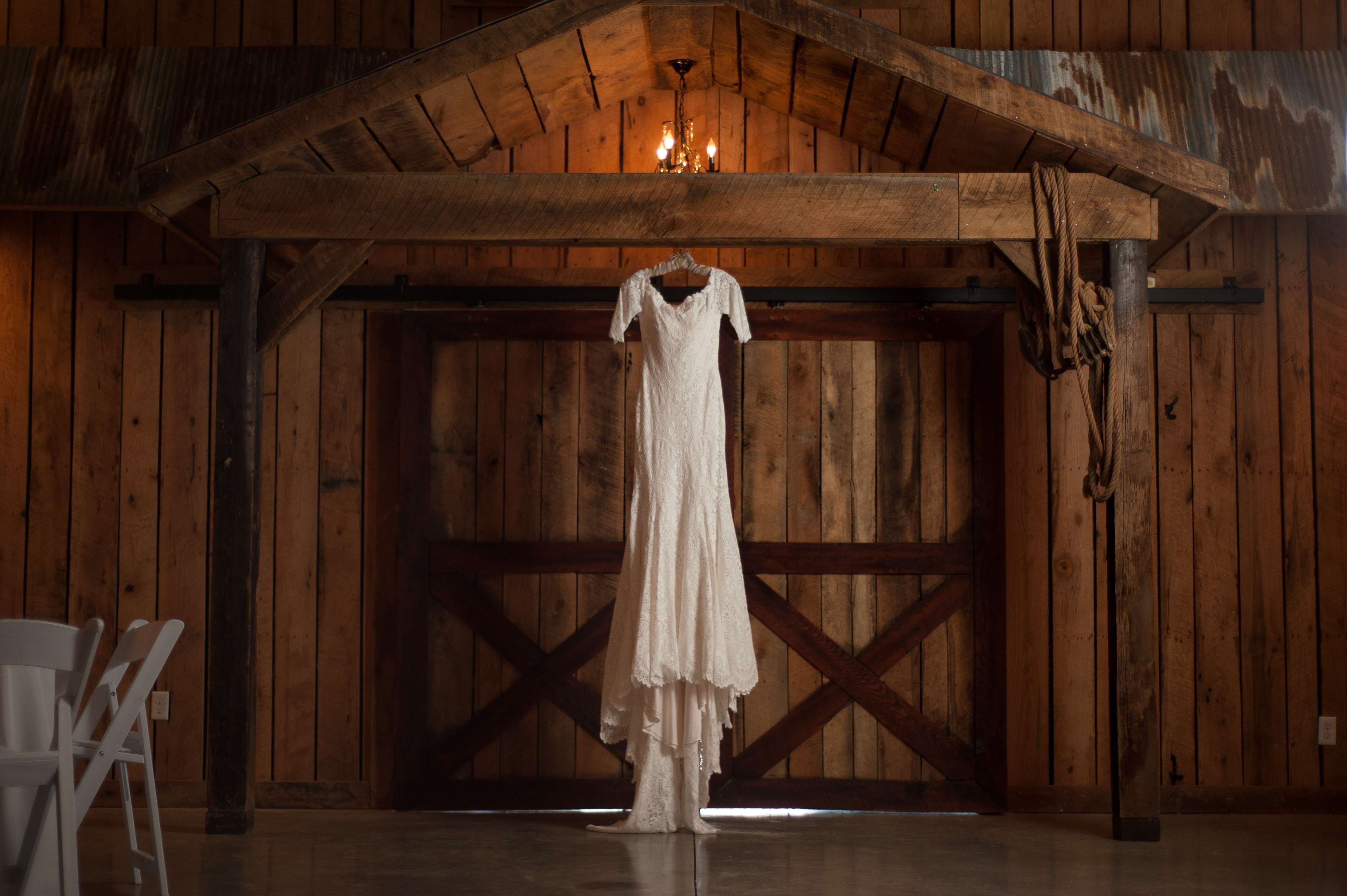 Wedding dress hanging from doorway with dramatic lighting.