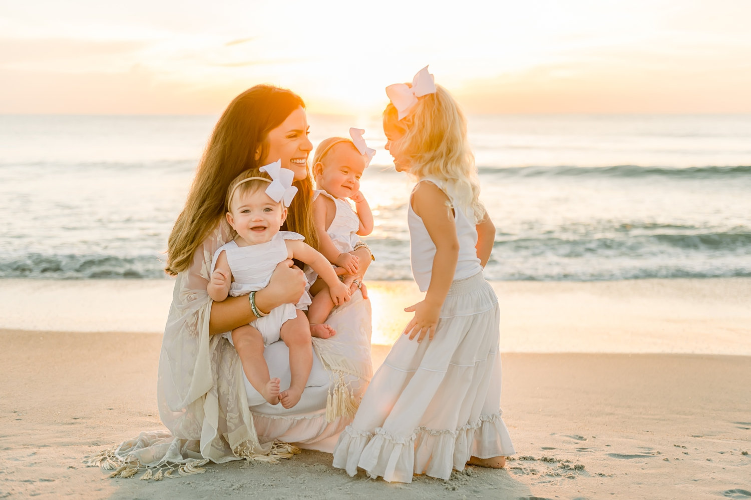 mother holding twin girls, little girl looking at her mom and sisters, sunrise